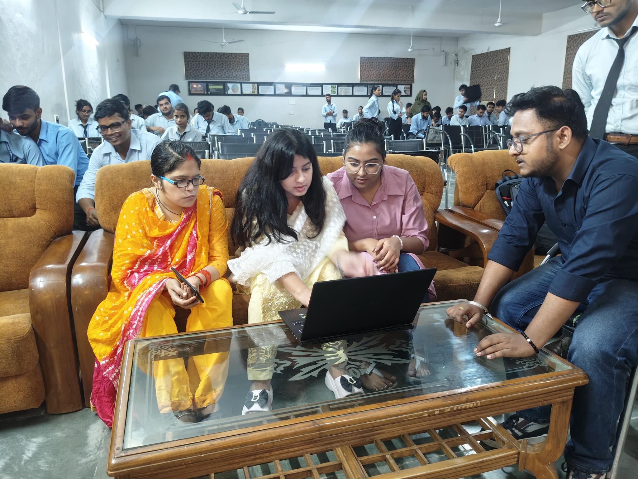 Students and a mentor reviewing work together on a laptop at Vision Kanpur